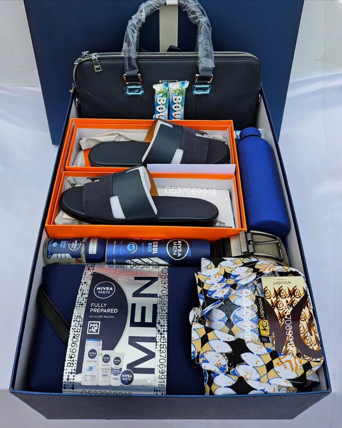 Gift box for men containing a handbag, slides, water bottle, and grooming products.