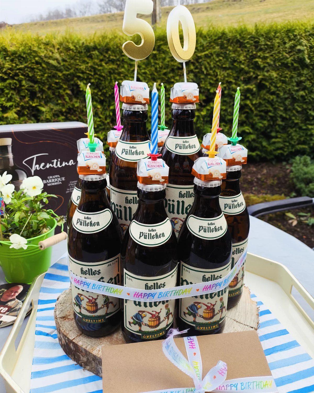 Small beer bottles on a wooden base with candles and gold 50 topper