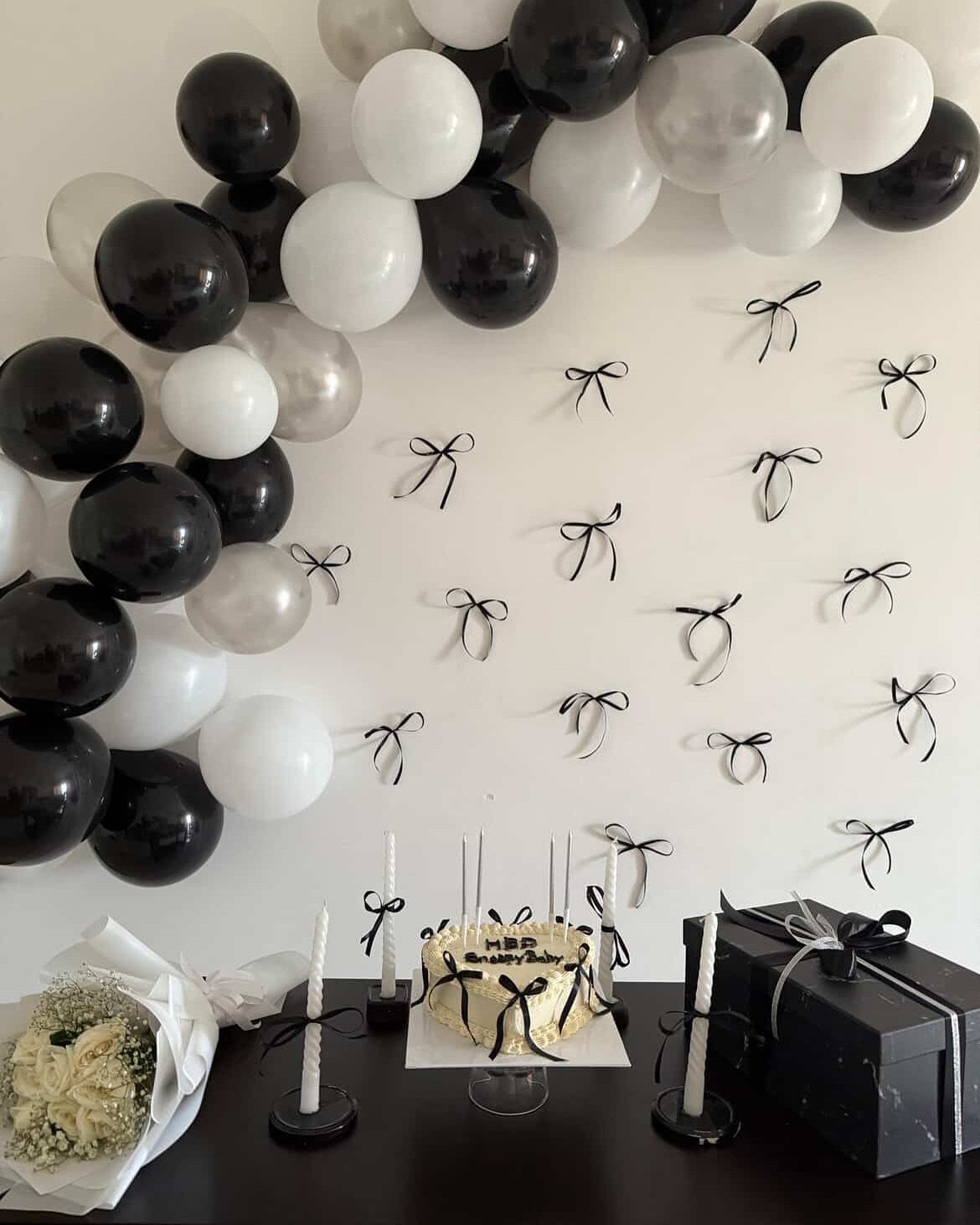 Black, white, and silver balloon arch with a matching cake and gift box.