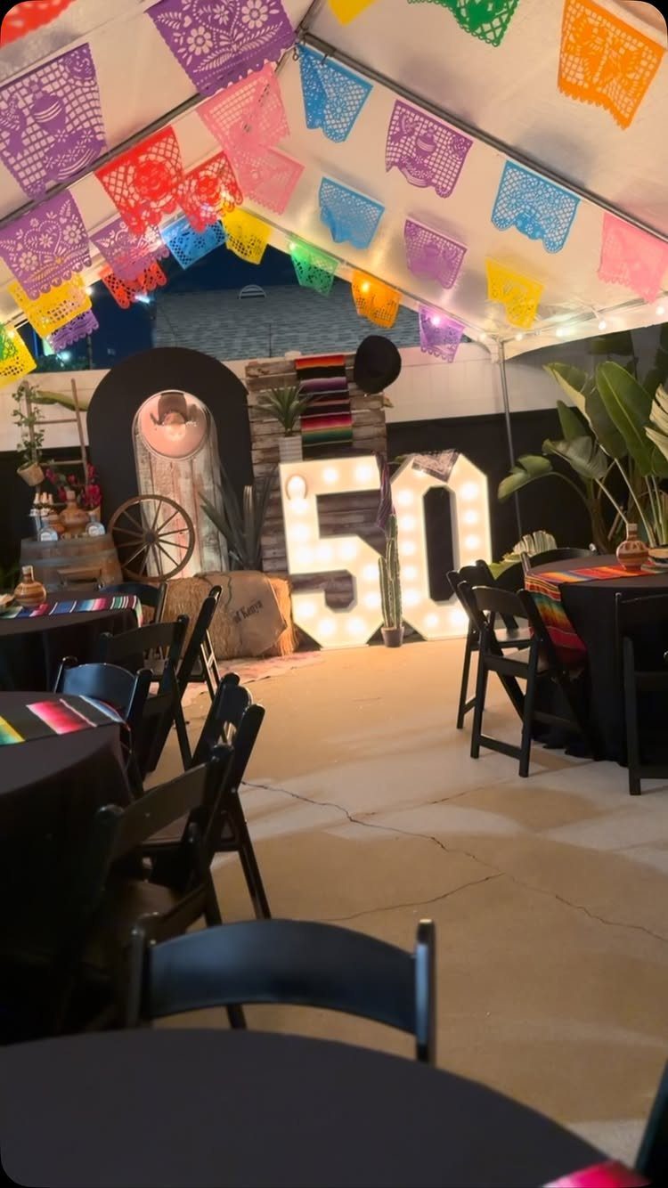 Fiesta themed 50th birthday party setup with colorful banners and large glowing numbers.