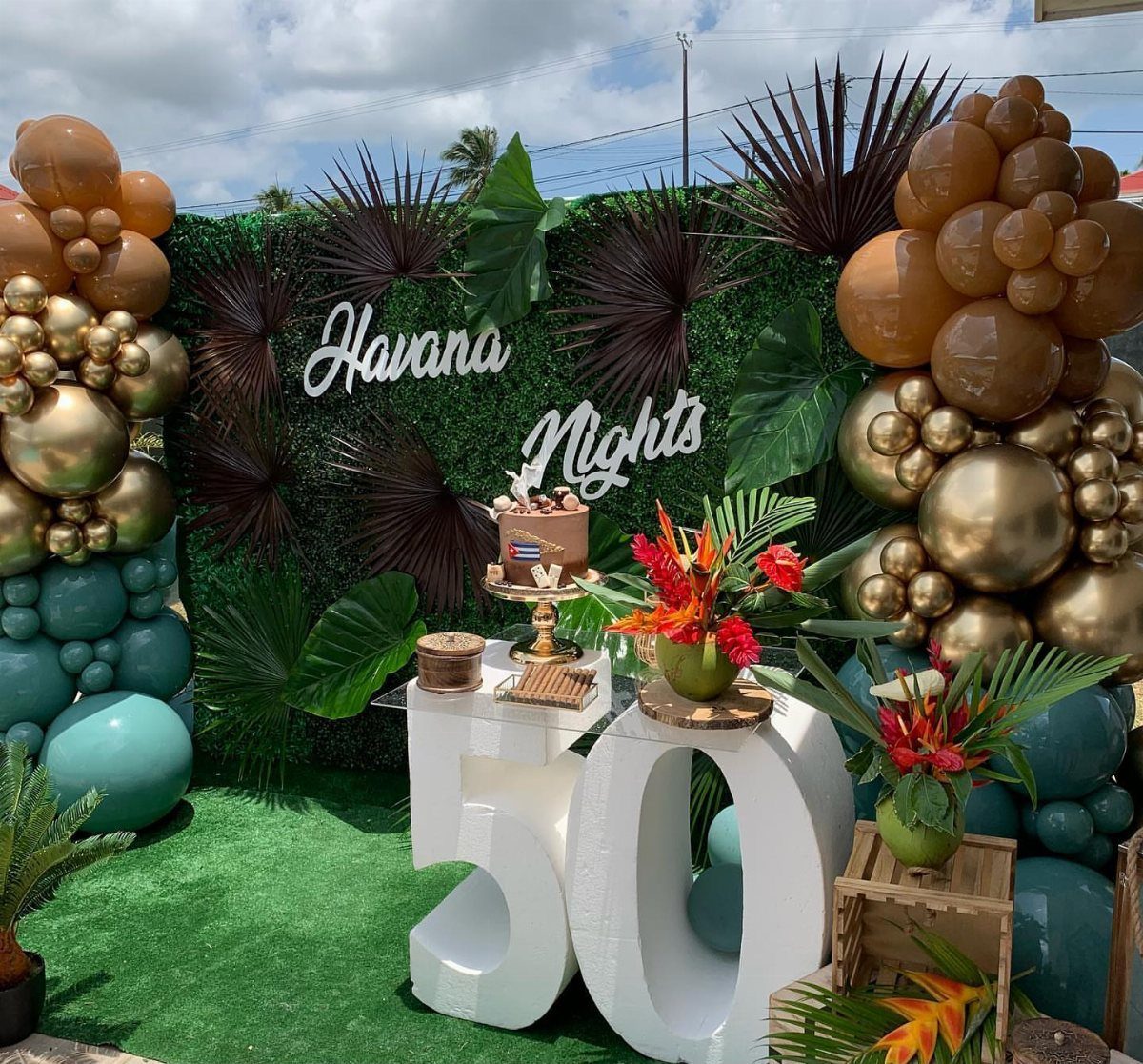 Havana Nights themed 50th birthday party with gold balloons and tropical greenery.