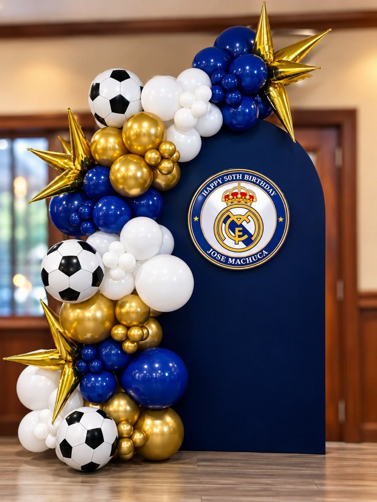 Blue arched backdrop with soccer ball balloons and Real Madrid logo for 50th birthday.