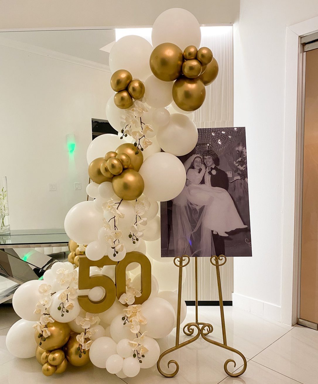 Gold and white balloon arch with a large 50 and wedding photo.