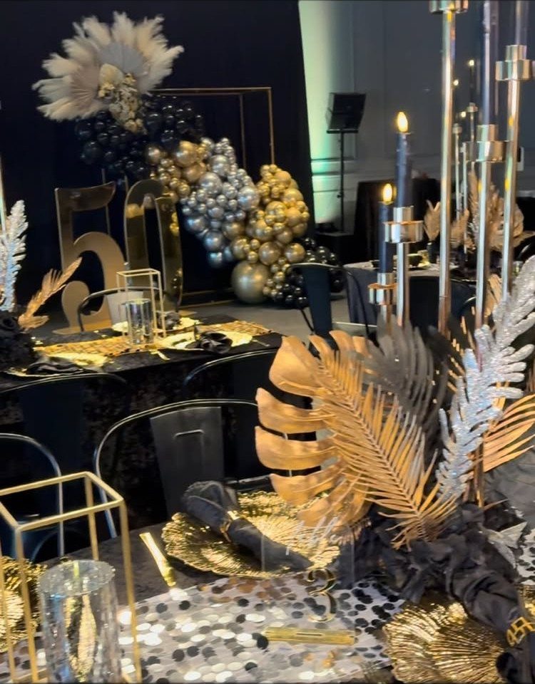 Gold metallic leaf centerpieces and tall candle holders on a confetti-covered table.