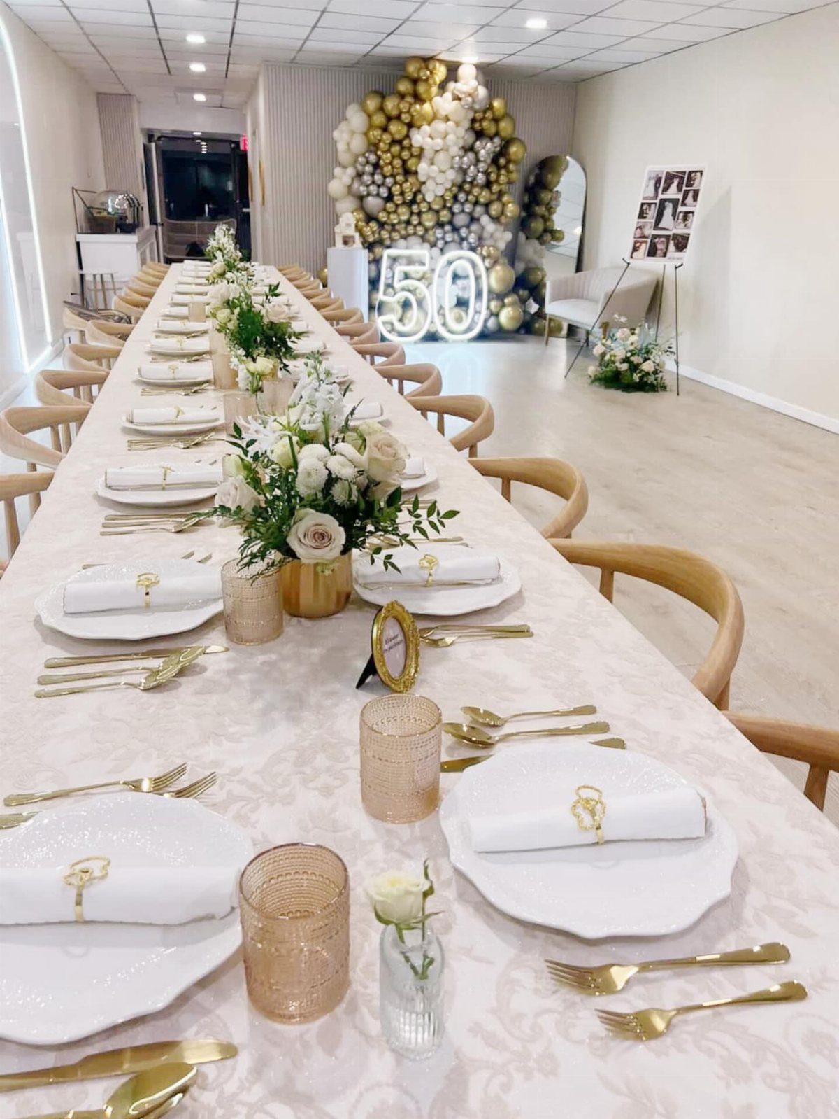 White patterned tablecloth with gold cutlery and floral centerpieces for a 50th anniversary.