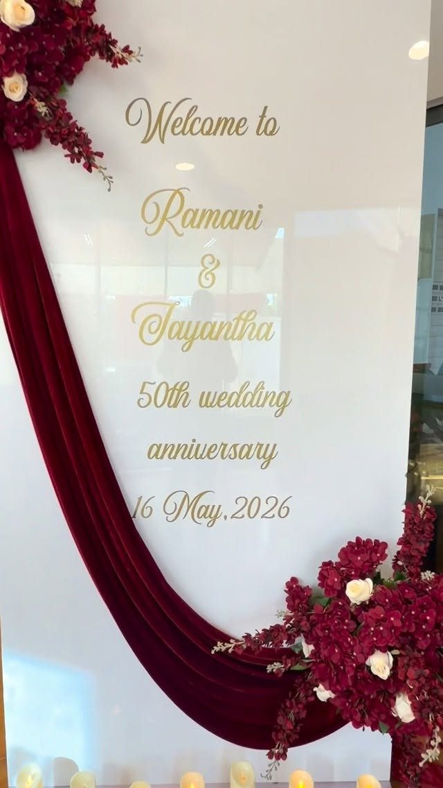 Welcome sign for 50th wedding anniversary with red velvet drape and floral arrangements