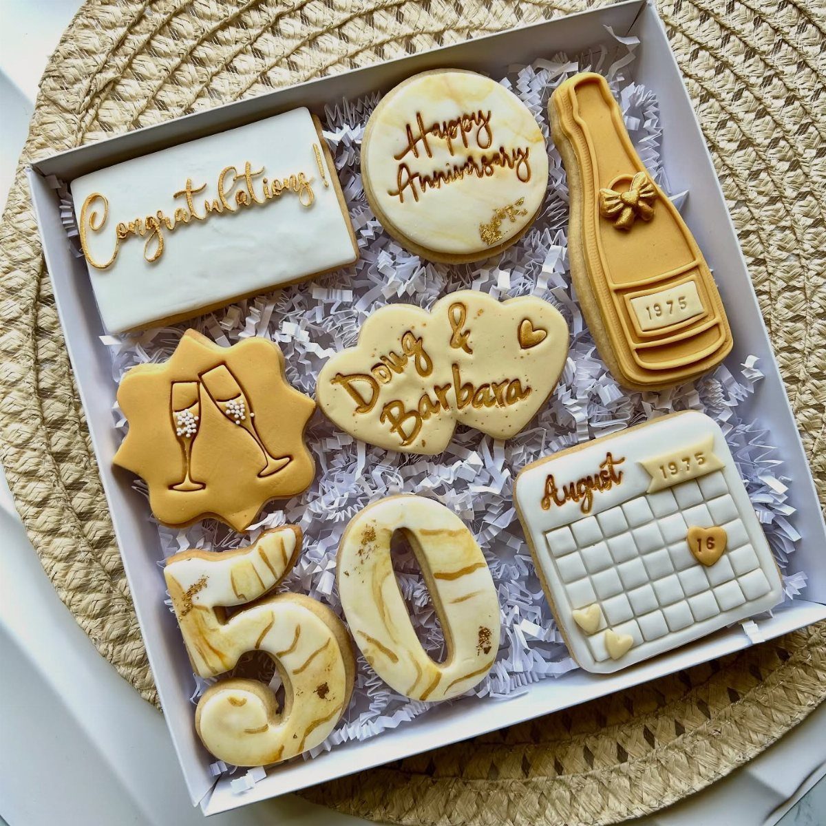 Decorated anniversary sugar cookies in a gift box with gold icing and numbers