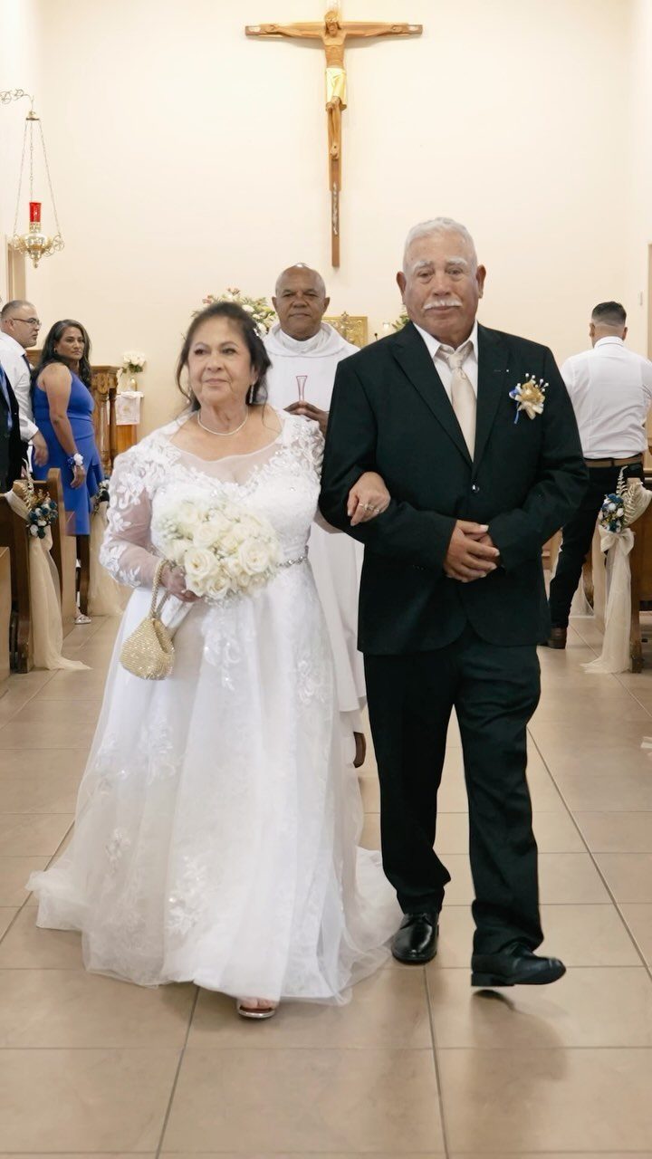 Older couple in wedding attire walking down a church aisle after a ceremony