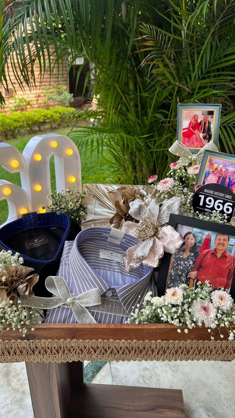 Gift arrangement with striped shirt, framed couple photos, and illuminated number 60.