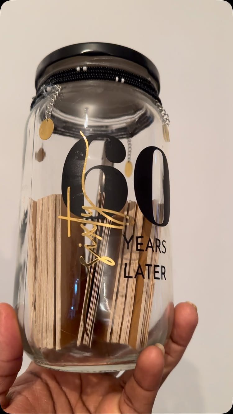Glass memory jar with wooden slats and 60 years later text held by hand