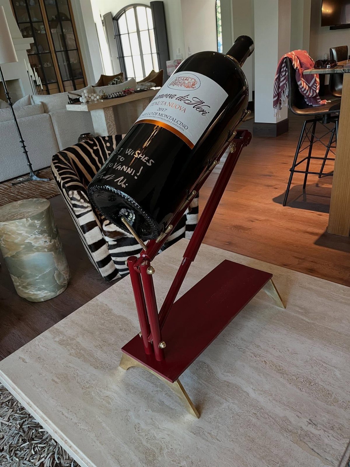 Wine bottle resting on a red metal angled holder on a marble table.