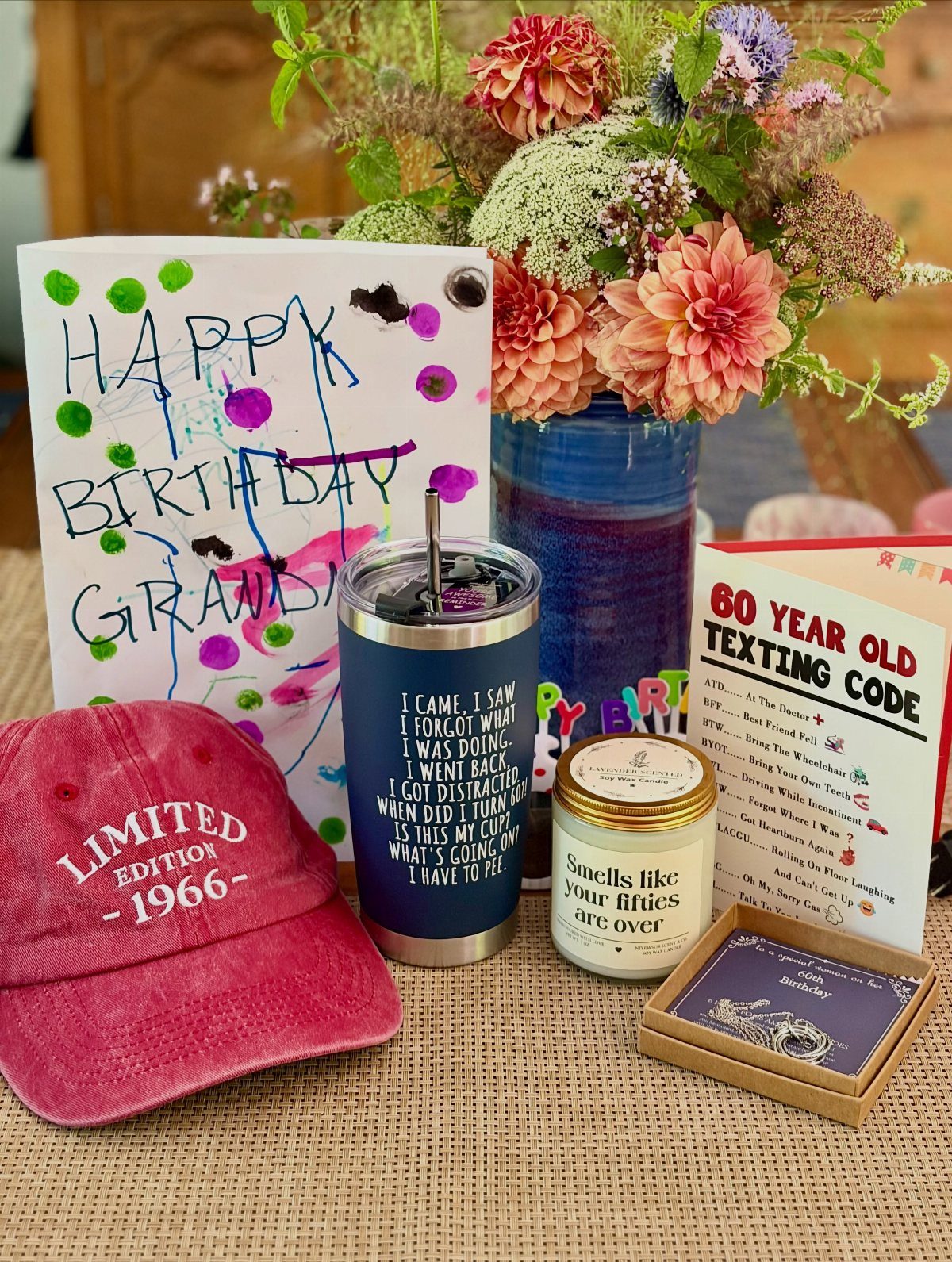 Birthday gift set with red cap, blue tumbler, and 60th birthday cards.