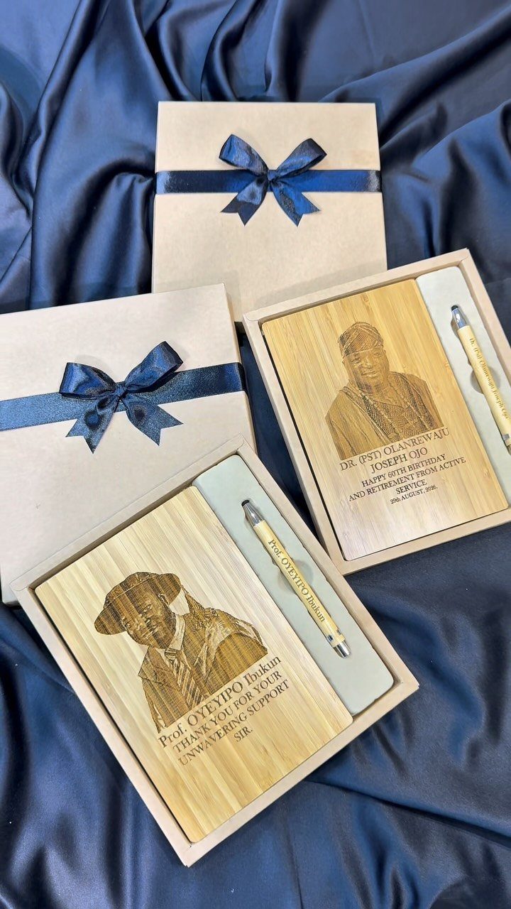 Personalized wooden notebooks and pens in gift boxes on navy blue satin fabric