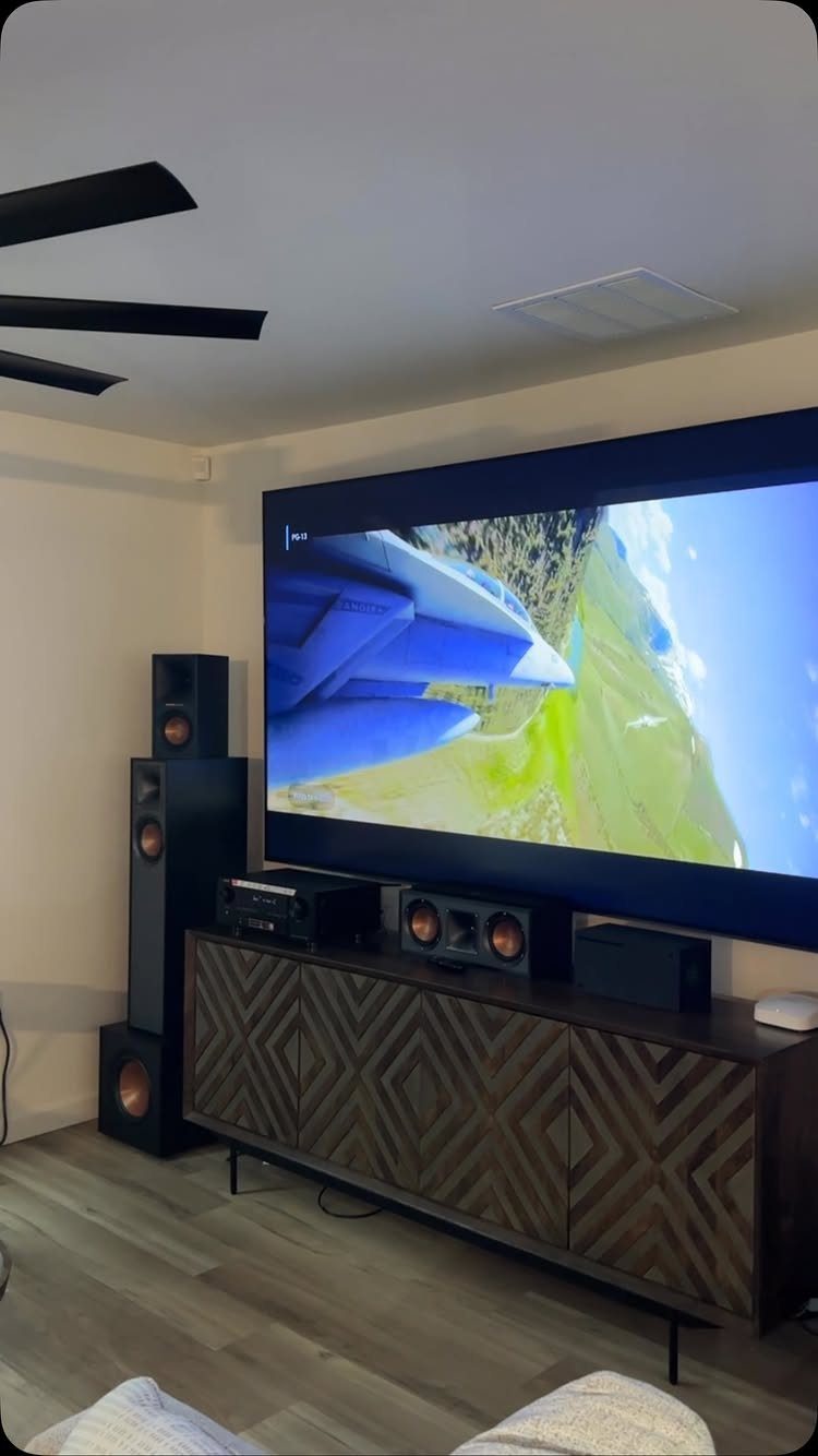 Home theater sound system with black speakers and a large screen in a living room.