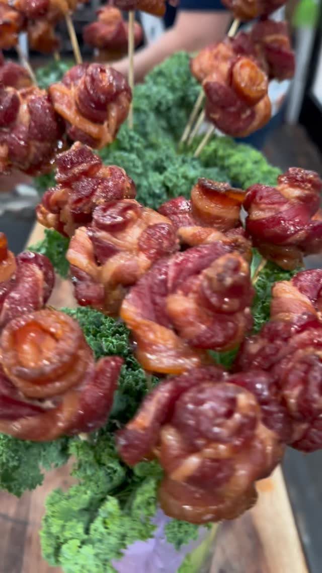 Bacon roses on skewers arranged as a bouquet with curly kale foliage.