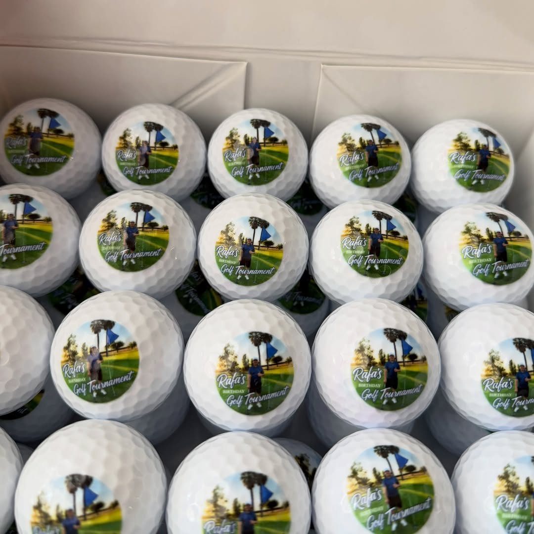 White golf balls in a box featuring custom printed golf tournament graphics.