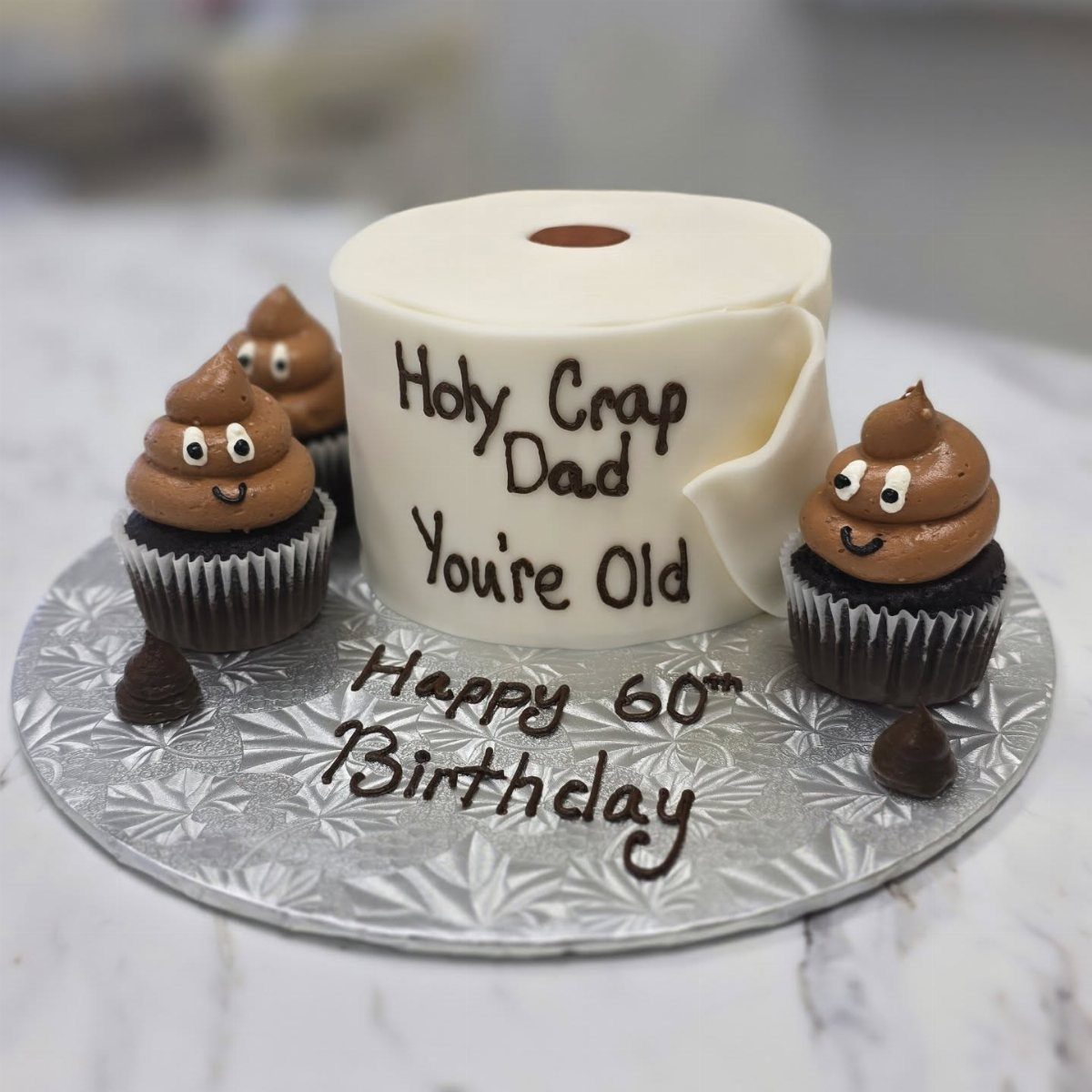 Toilet paper roll cake and poop emoji cupcakes for a 60th birthday celebration.