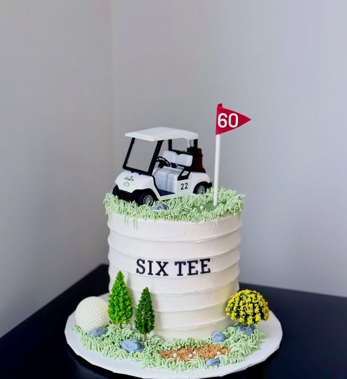 Golf themed birthday cake with a miniature golf cart and red 60 flag.
