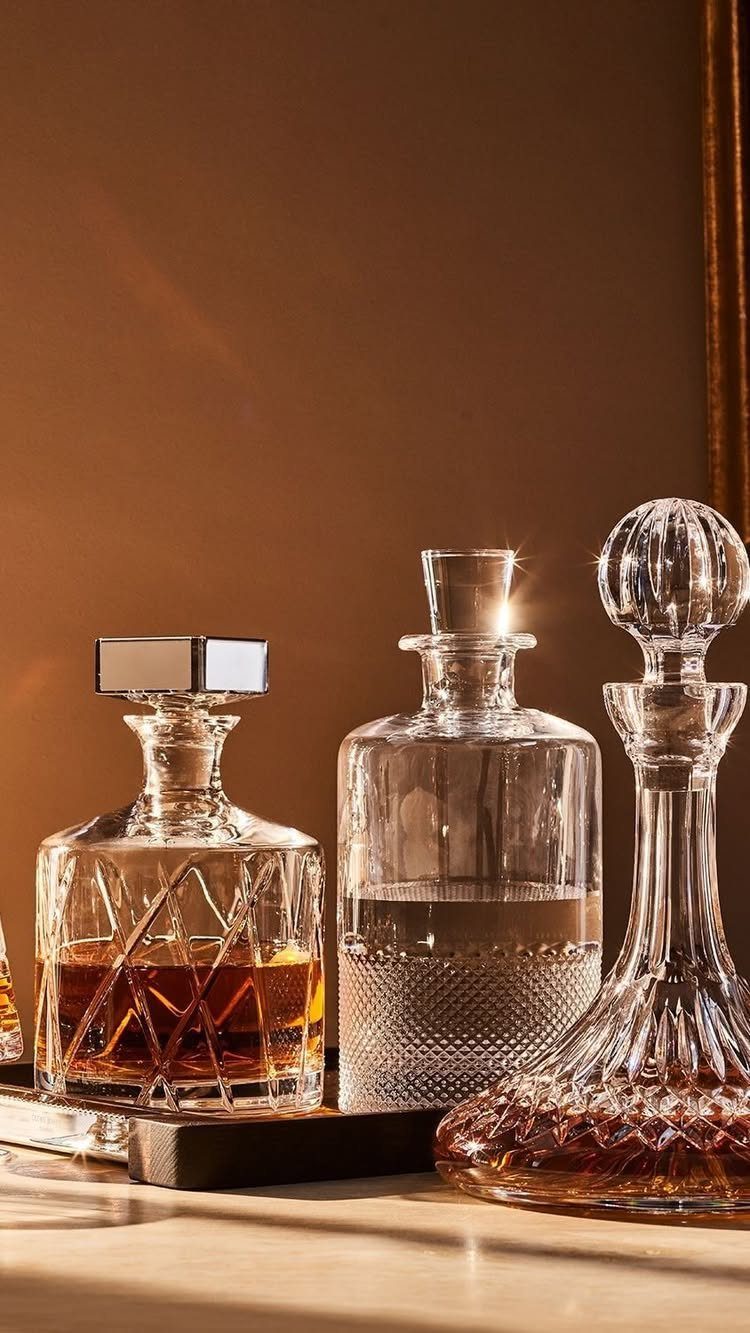 Three ornate glass whiskey decanters filled with amber liquor on a dark tray.