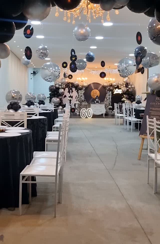 Event space decorated with disco balls, balloons, and a large number 60.