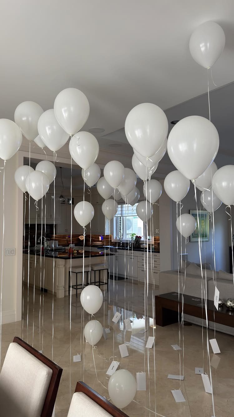 White balloons floating in a living room with small cards hanging from strings