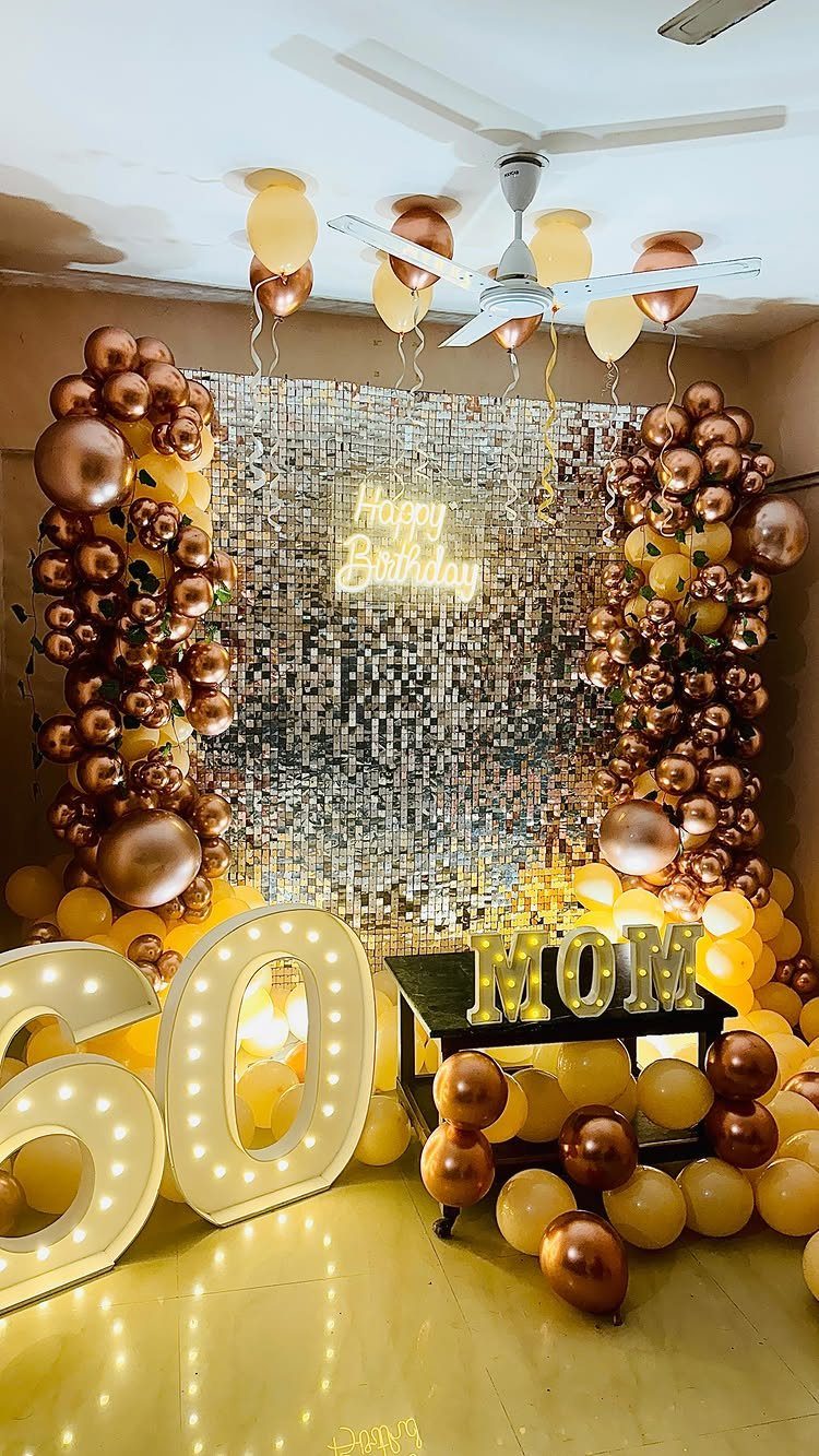Gold and bronze balloon decorations with large glowing 60 numbers for a birthday.