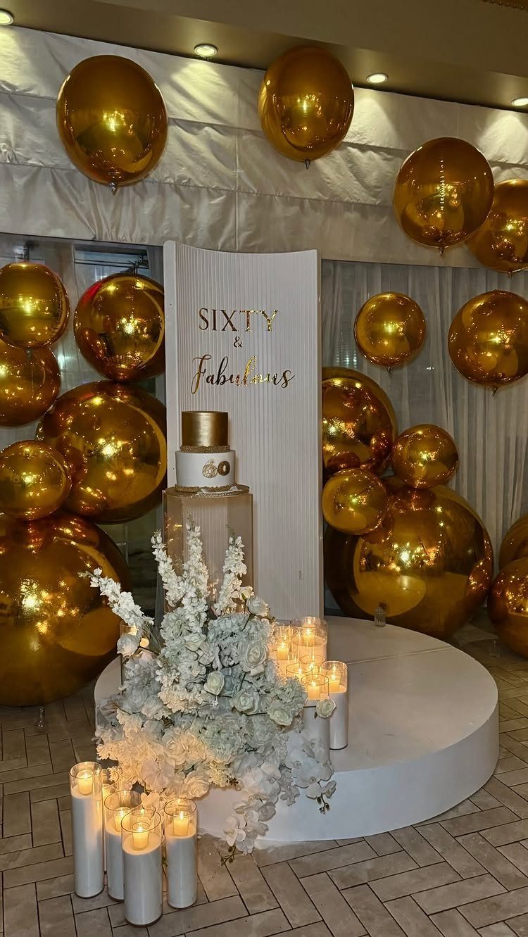 Gold balloons and white flowers surrounding a sign that says Sixty and Fabulous