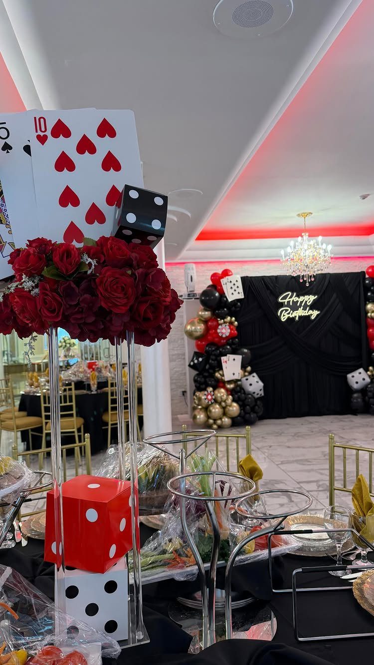 Casino themed birthday party decorations with red roses, dice, and playing card centerpieces.
