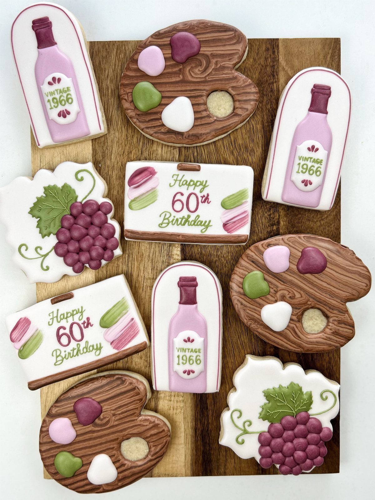 Custom 60th birthday cookies shaped like wine bottles, artist palettes, and grapes.