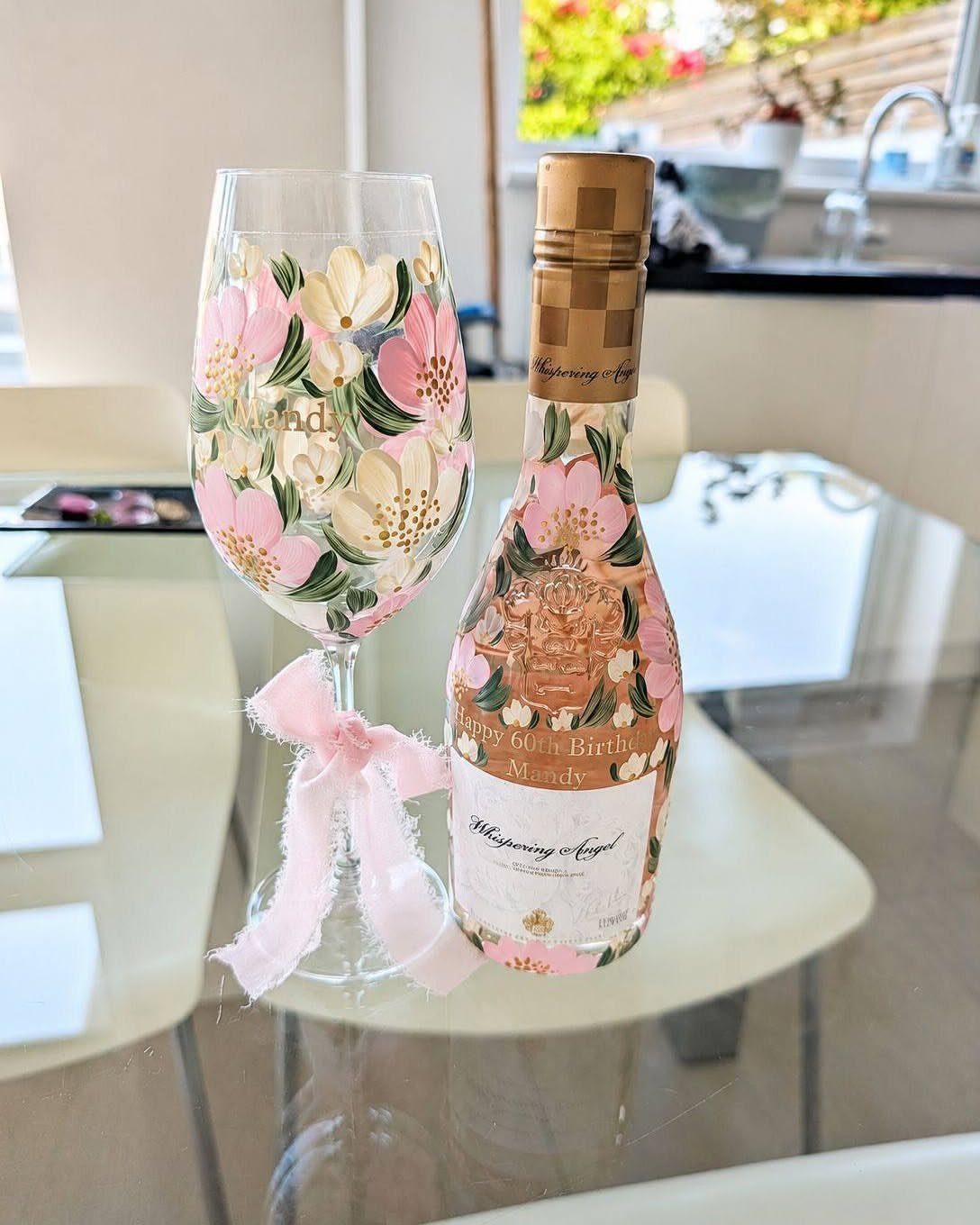Rosé wine bottle and matching floral wine glass with a pink ribbon bow.