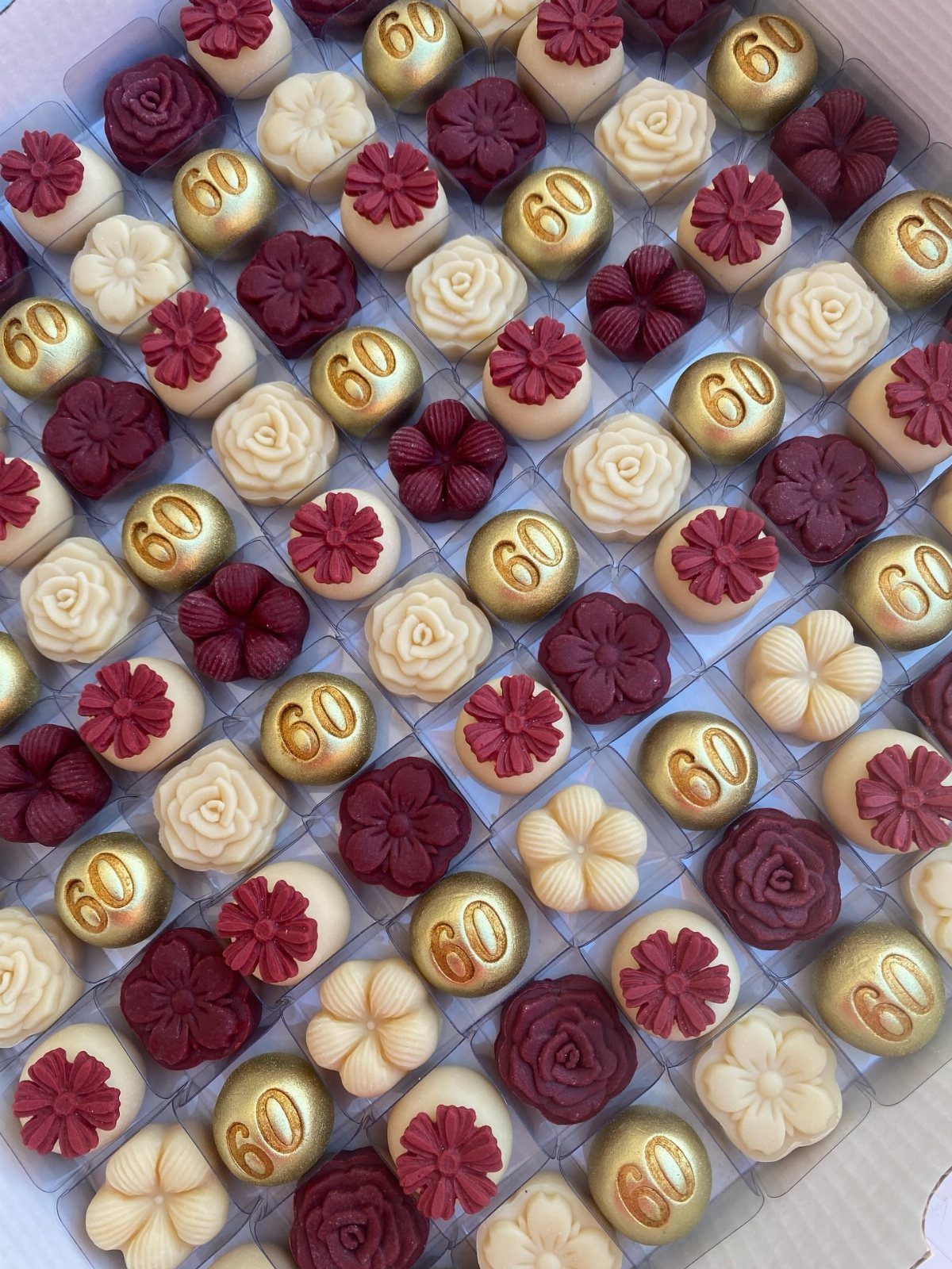 Gourmet chocolates in gold, white, and red, some featuring the number 60.