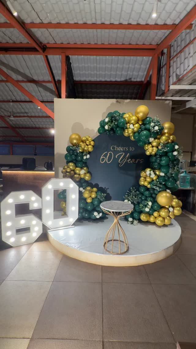 60th birthday party decoration with gold and green balloons and illuminated numbers