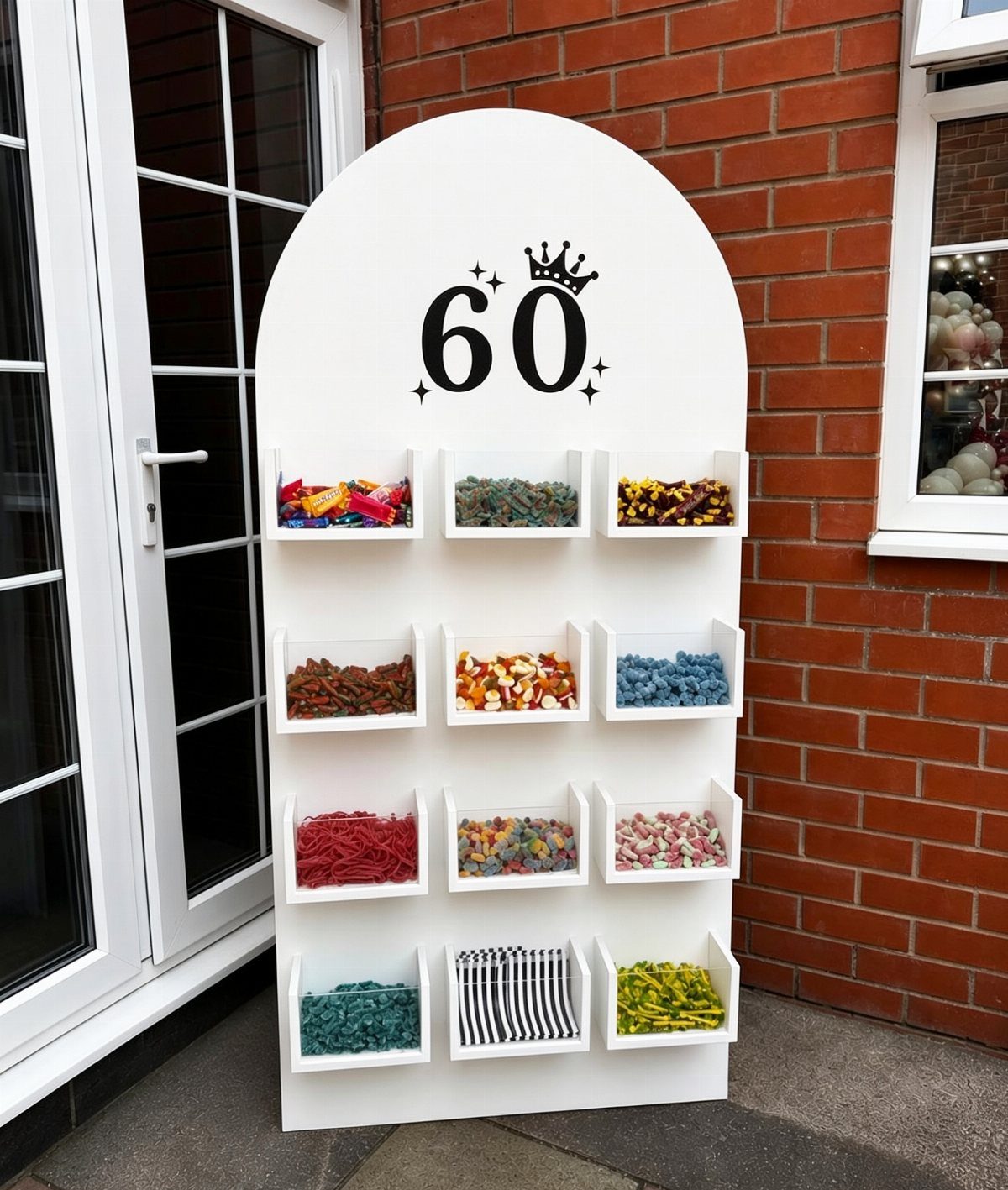 White arched candy wall with colorful sweets and the number 60 for a birthday.