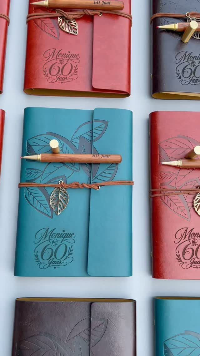 Leather-bound journals in red and teal embossed with Monique and 60 years.