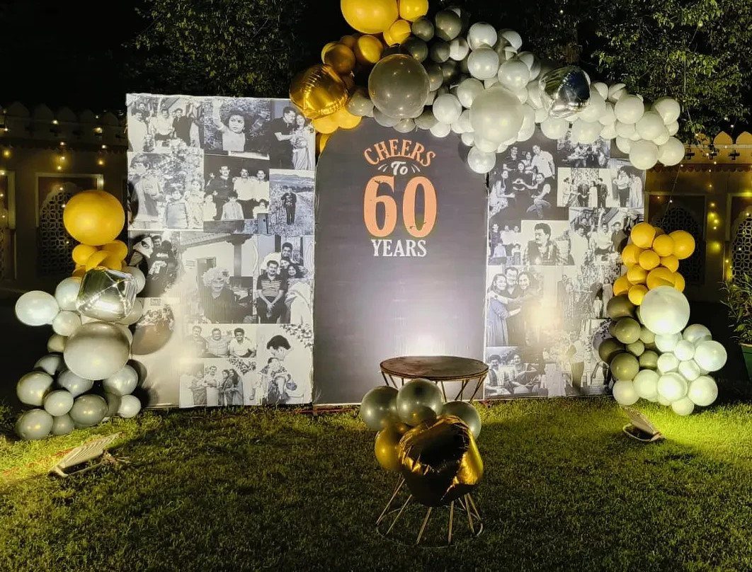 60th birthday party backdrop with nostalgic photo panels and gold and white balloons