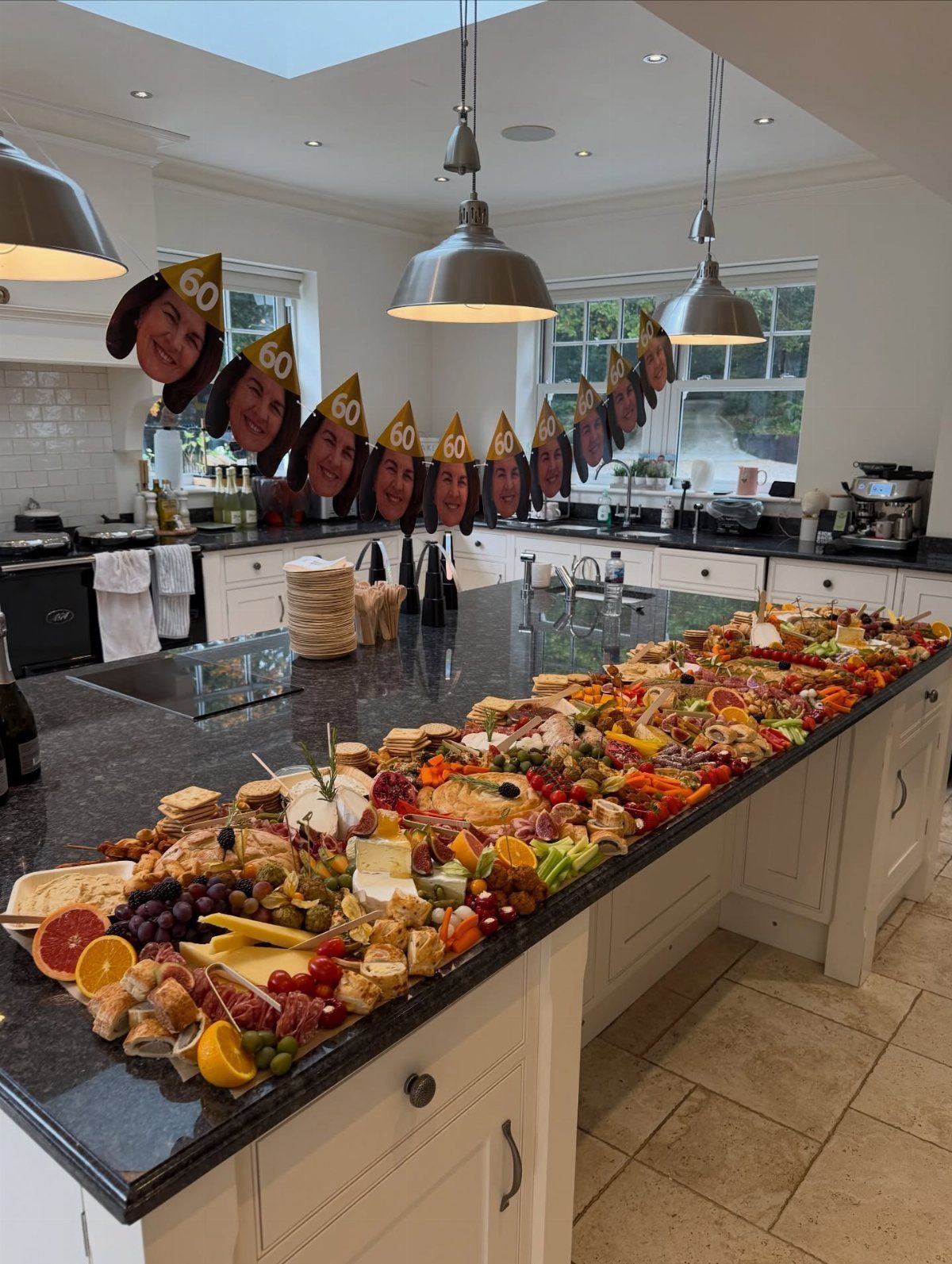 Grazing platter on a kitchen island with custom 60th birthday party hats above.