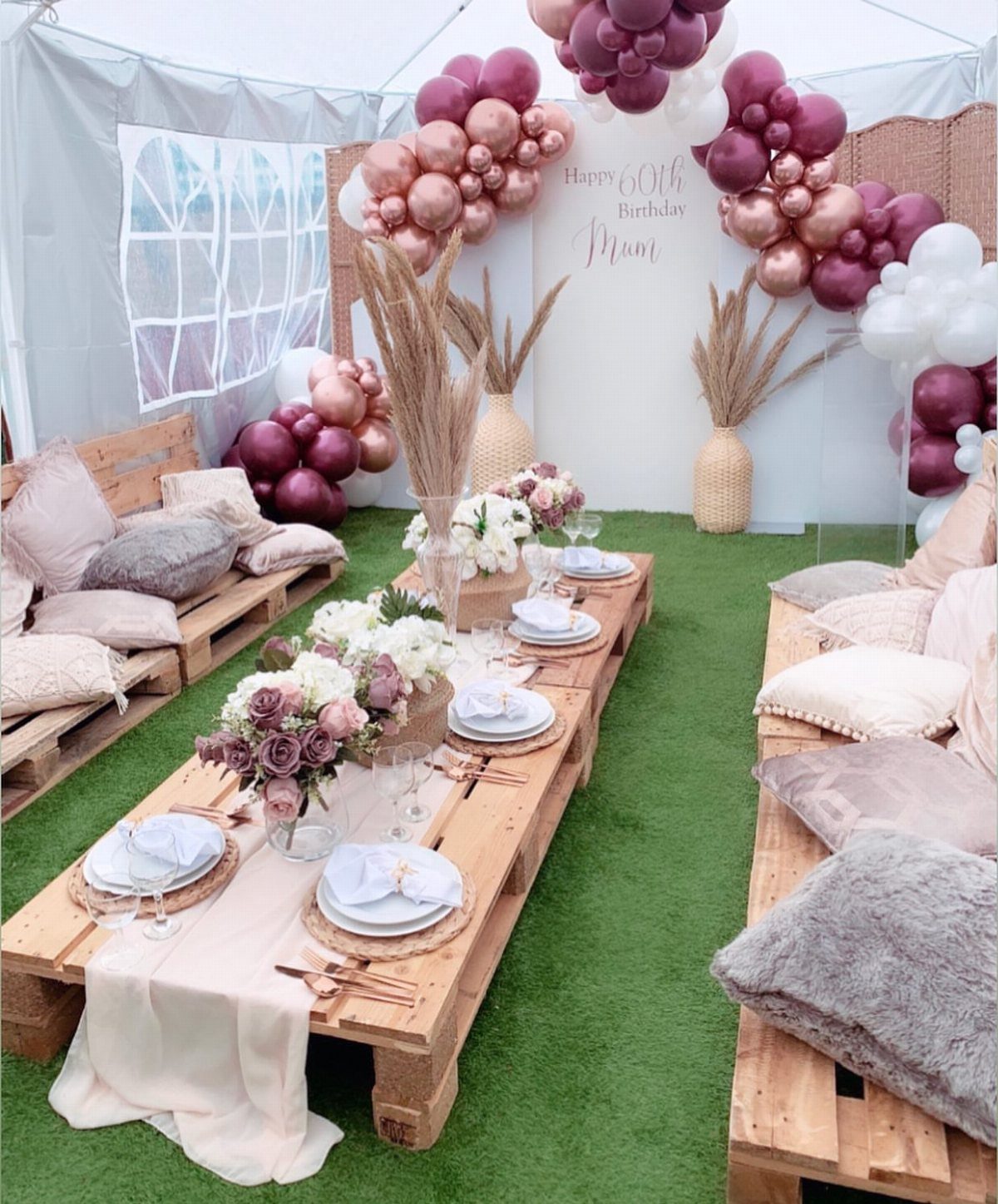 Low pallet table set for a picnic with floral arrangements and balloon decor.