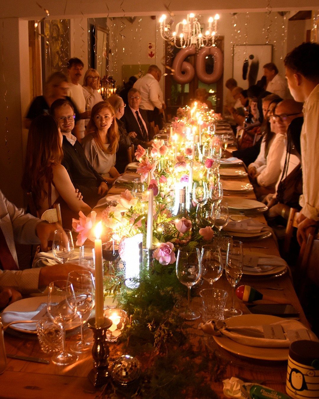 Long decorated dining table with candles and flowers for a 60th birthday dinner