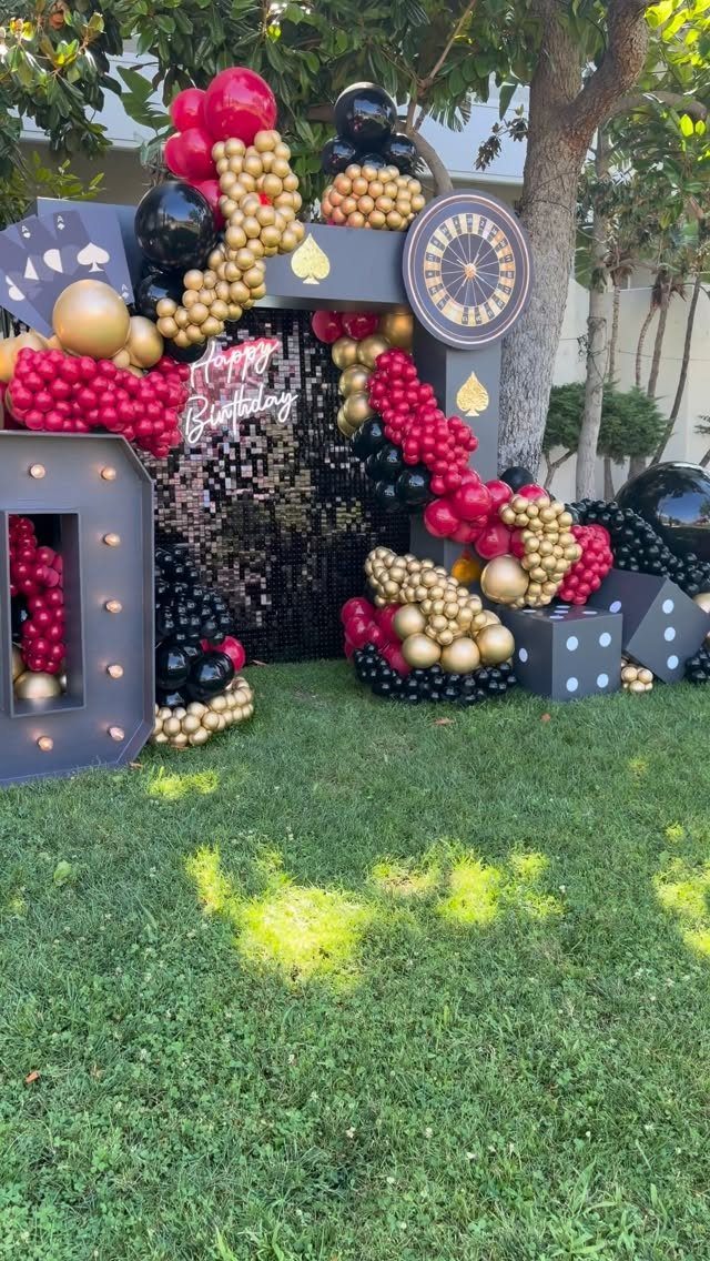 Casino themed birthday decorations with red and gold balloons, dice, and roulette wheel.