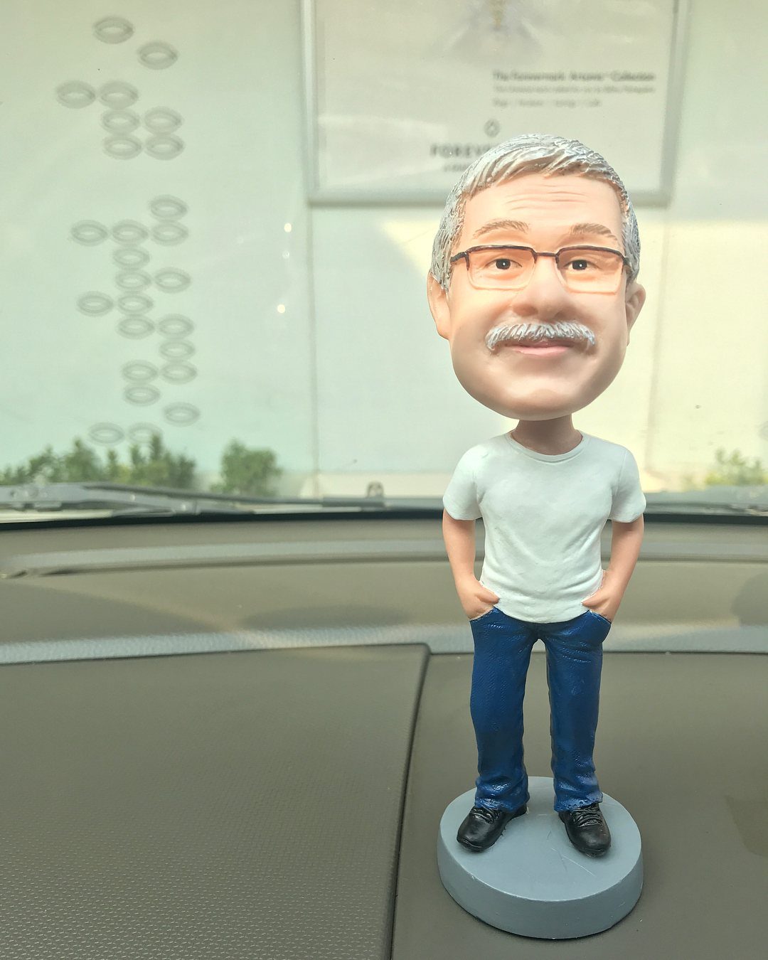 Custom bobblehead of an older man with glasses and mustache on car dashboard