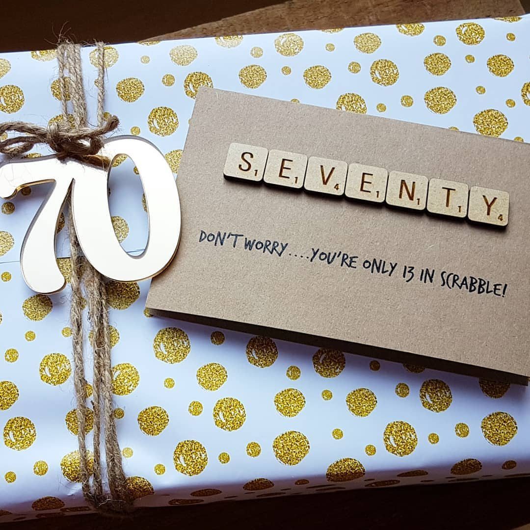 Wrapped gift with gold polka dots, a wooden 70, and a Scrabble tile card.