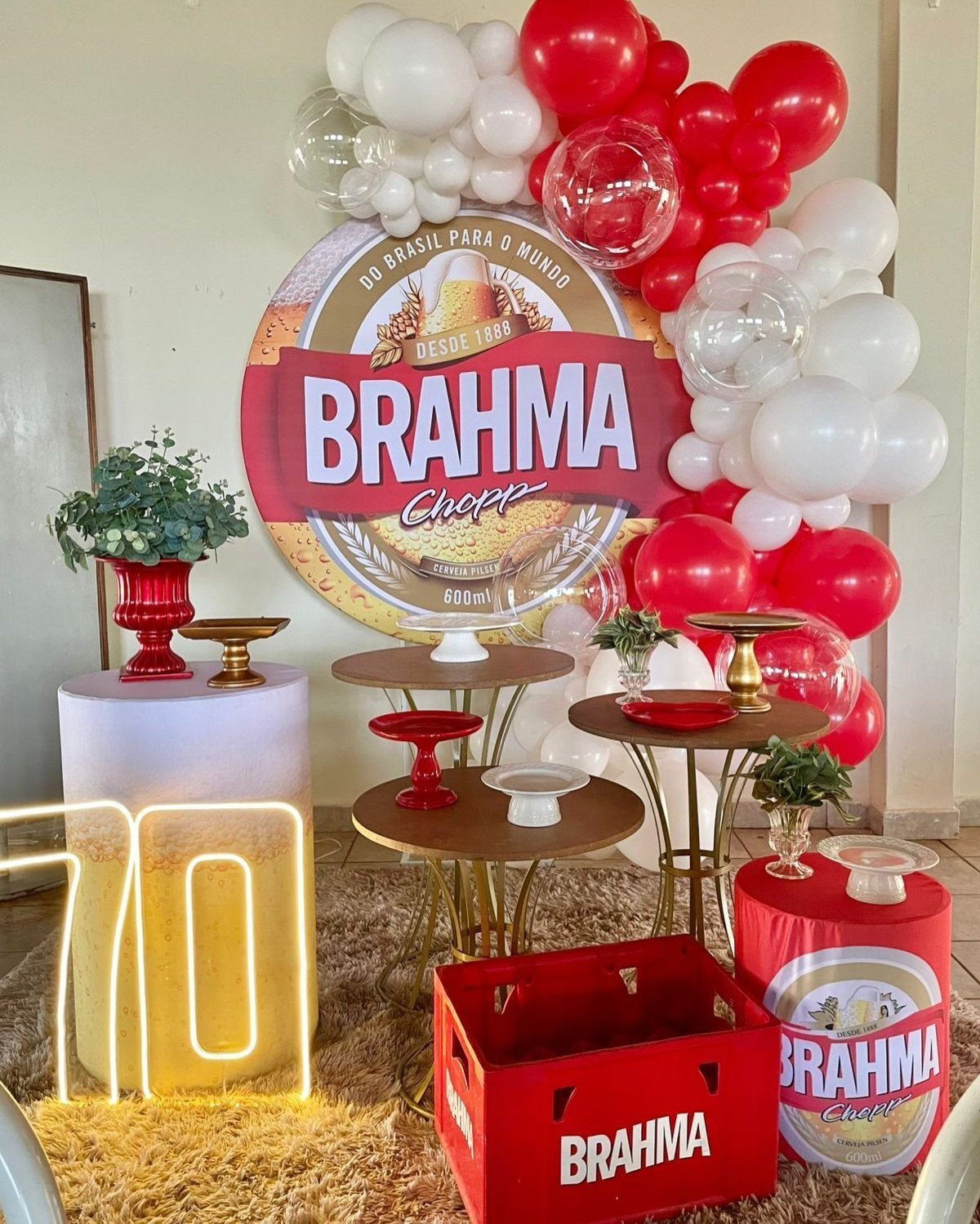 Birthday party decoration with red and white balloons, Brahma beer branding, and glowing 70.