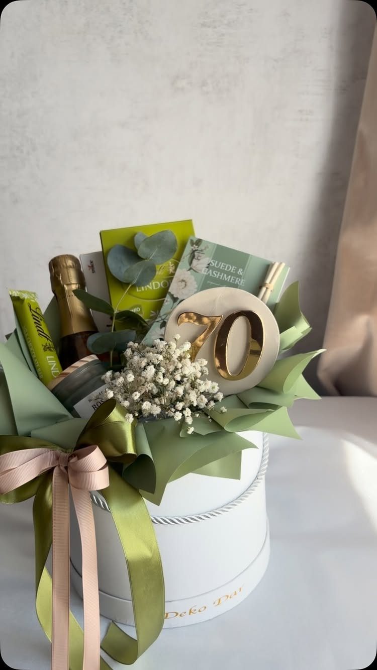 Gift hamper with sparkling wine, treats, and a wooden 70th birthday sign.