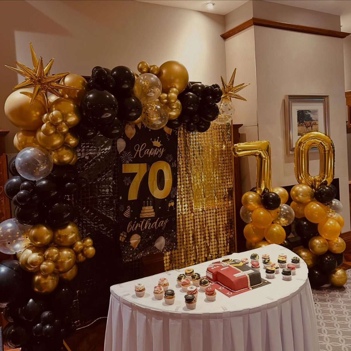 Birthday party decorations with gold and black balloons and a 70th birthday banner.