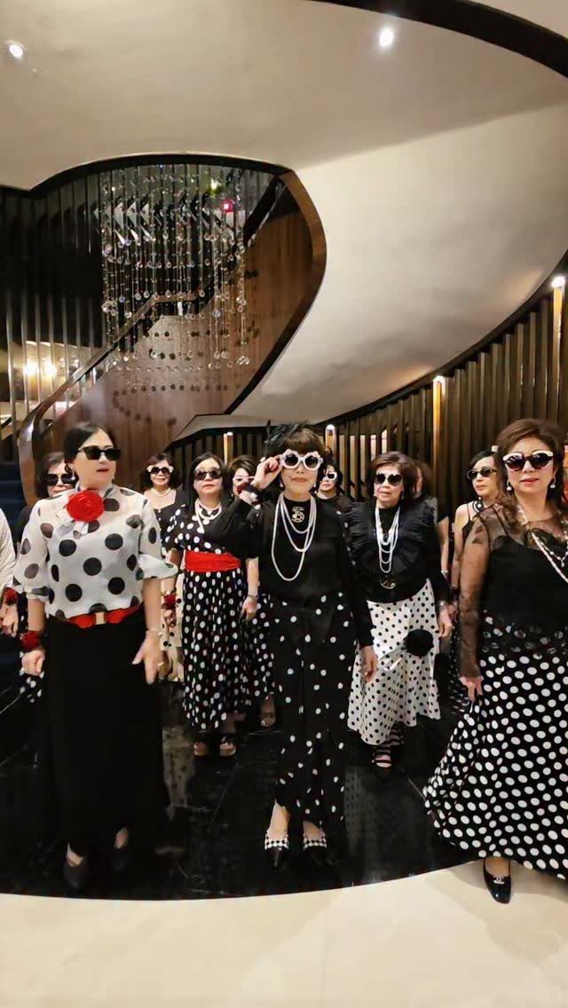 Mature women in black and white polka dot outfits posing in a modern lobby