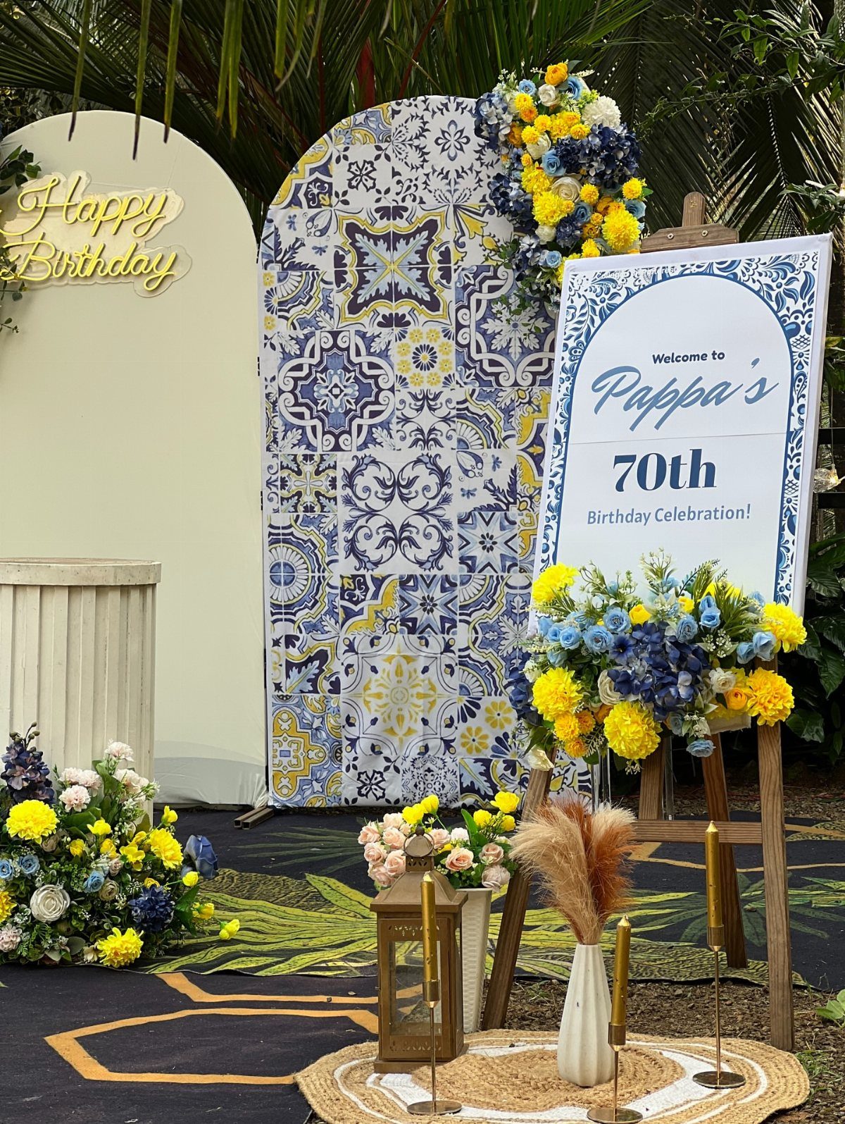 Birthday party decoration with blue tile backdrop and 70th birthday welcome sign.