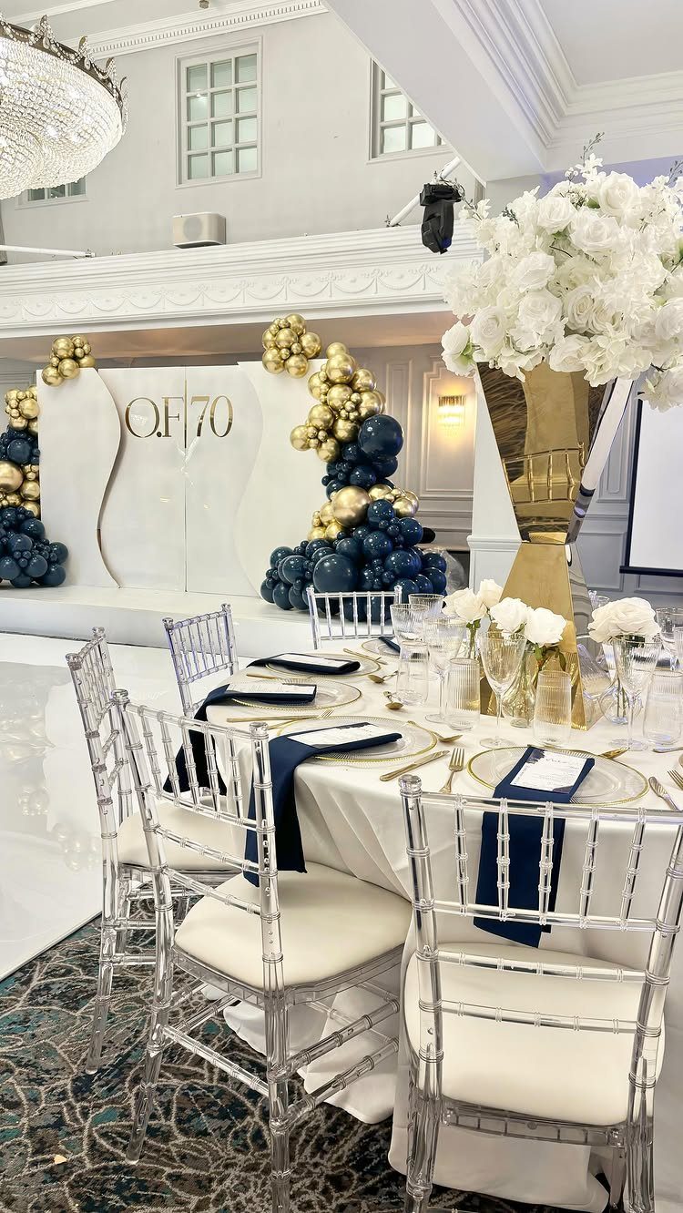 Elegant 70th birthday party setup with navy and gold balloons and white florals