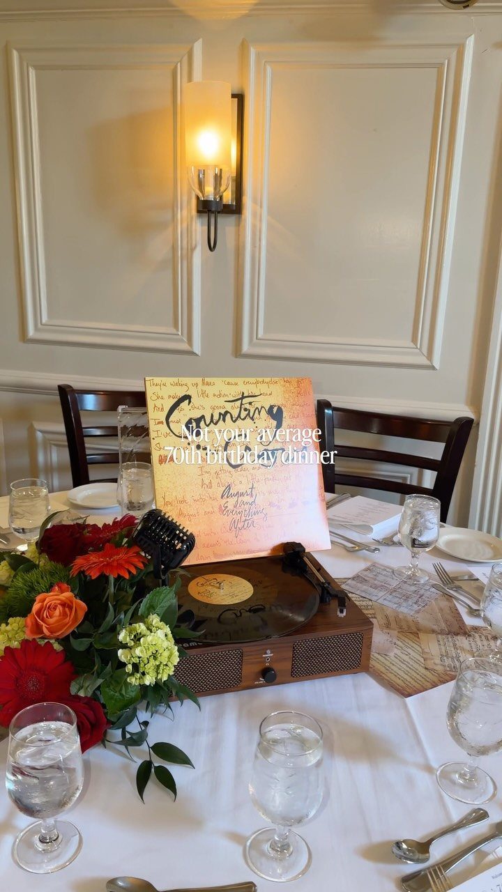 Dinner table setting with flowers, a record player, and 70th birthday sign.