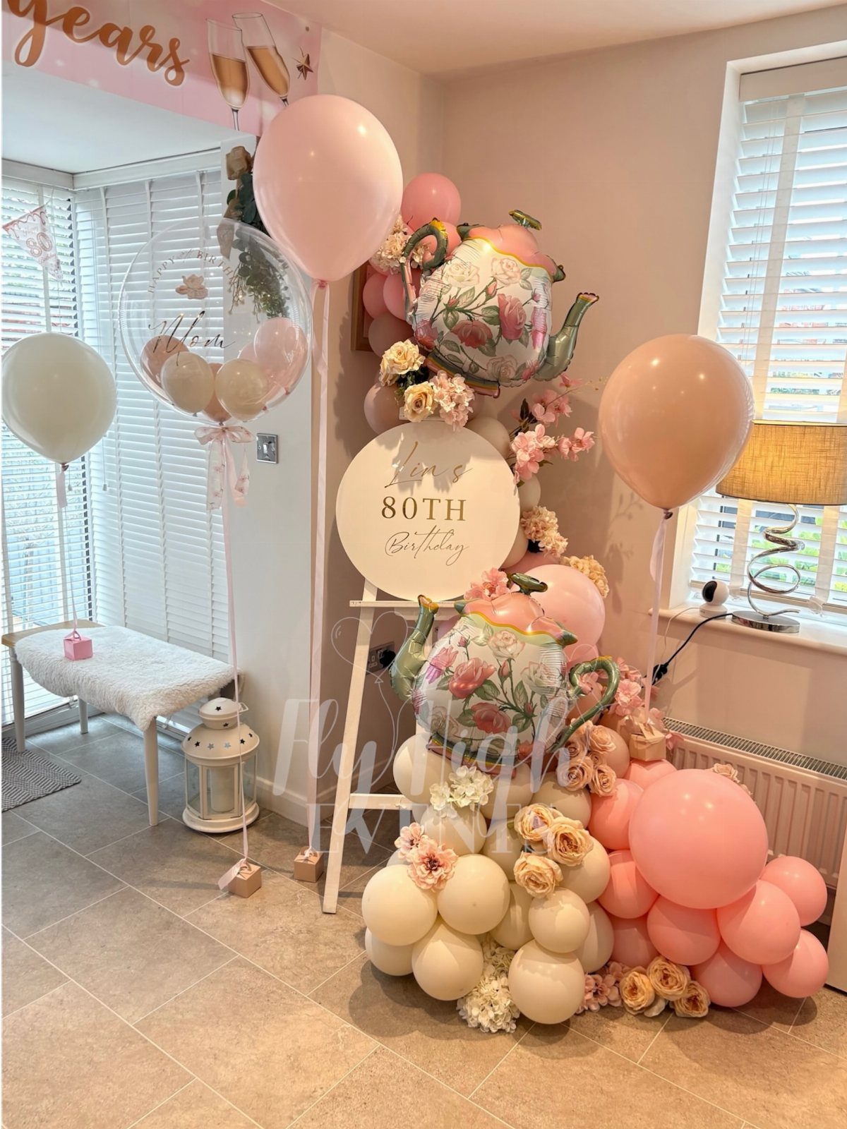 80th birthday party decorations with pink balloons, floral accents, and teapot-shaped balloons.