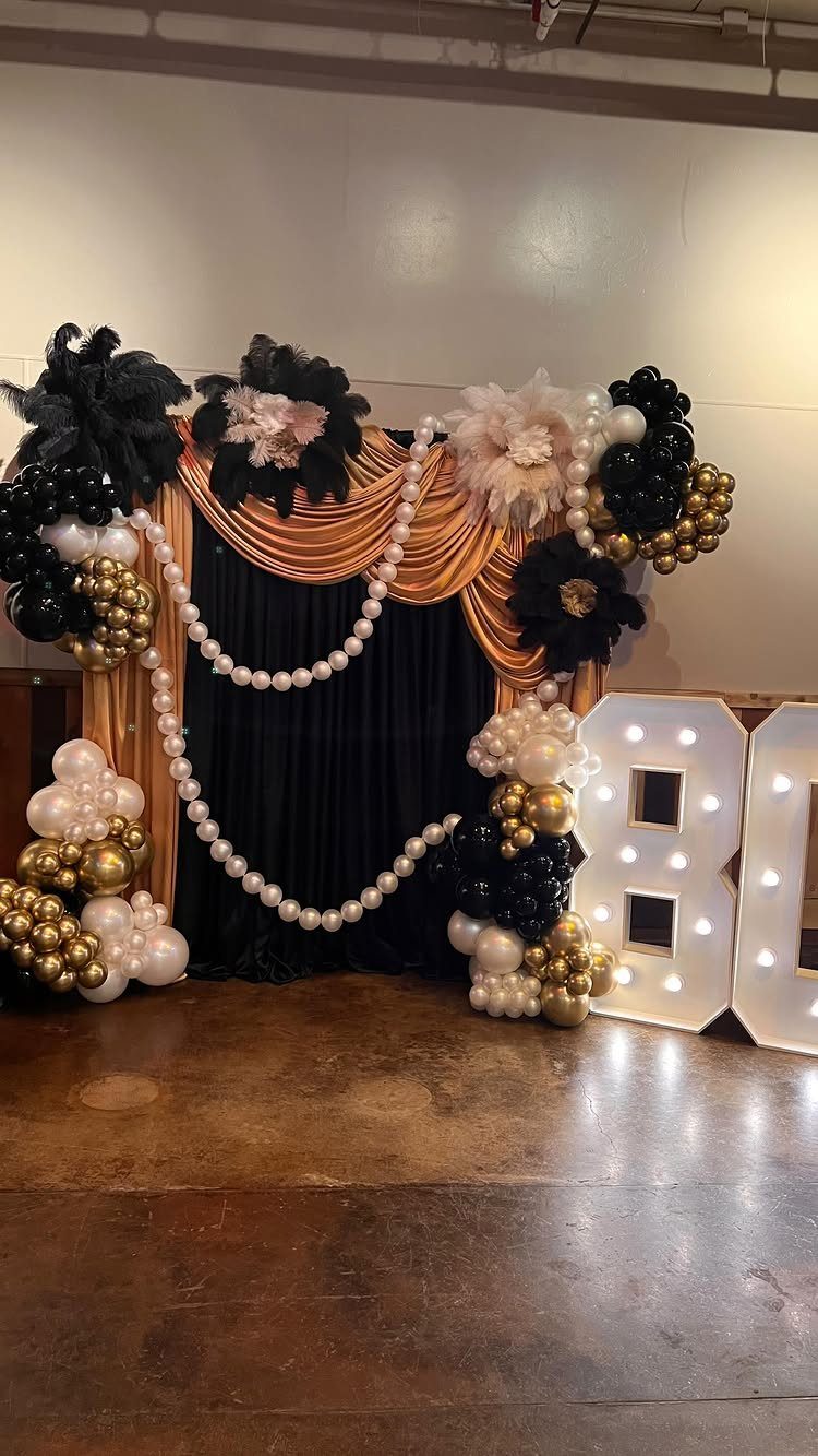 Gold and black party backdrop with pearl garlands and illuminated number 80